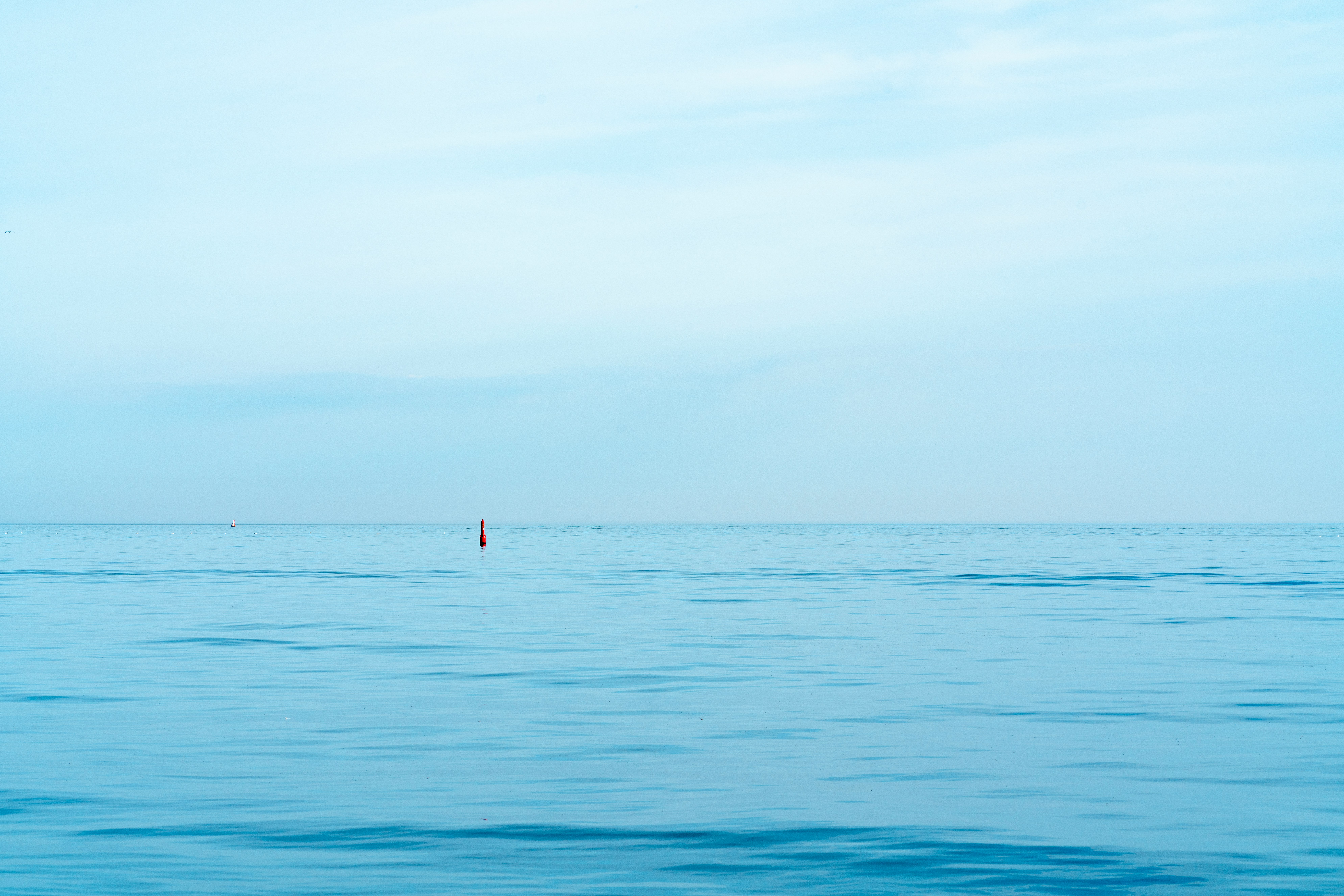 person in red shirt standing on blue sea during daytime